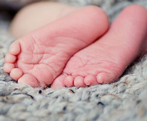 Pieds de nouveau-né dans les mains d’un adulte